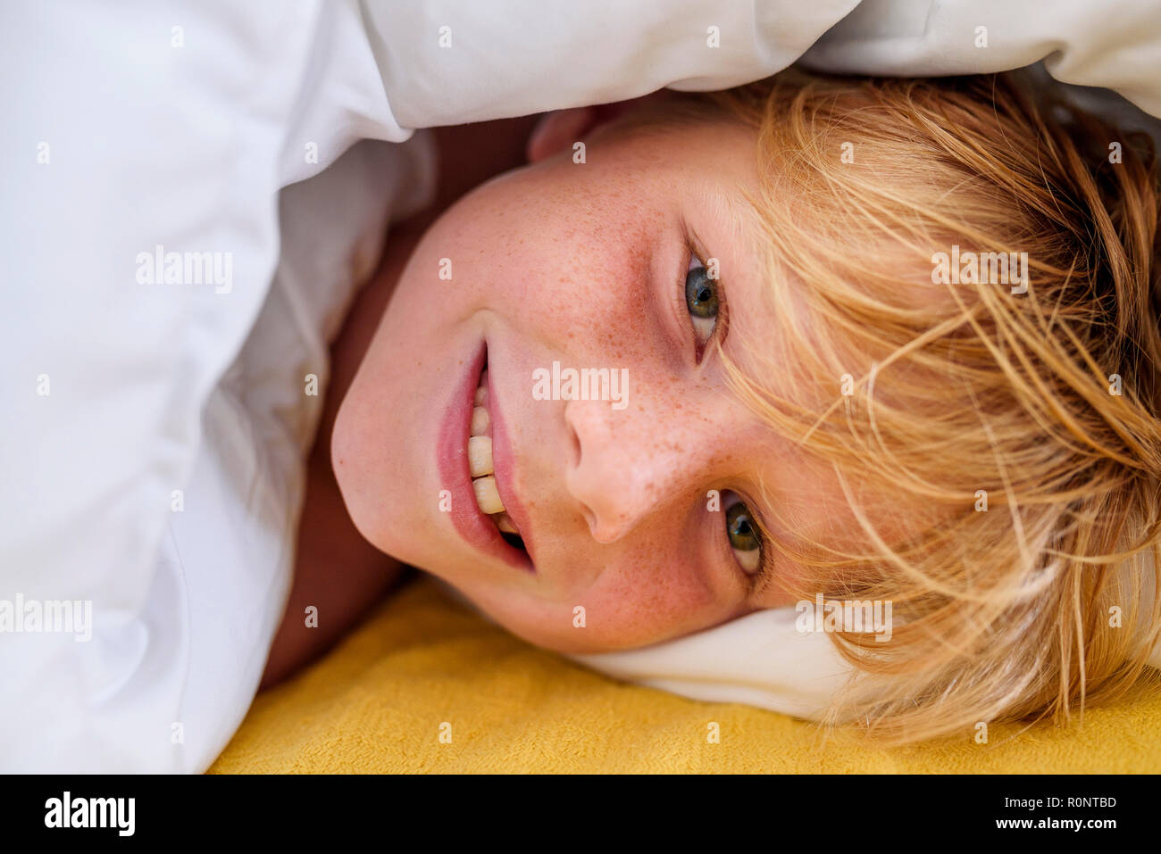 Portrait of a smiling boy lying in bed Stock Photo