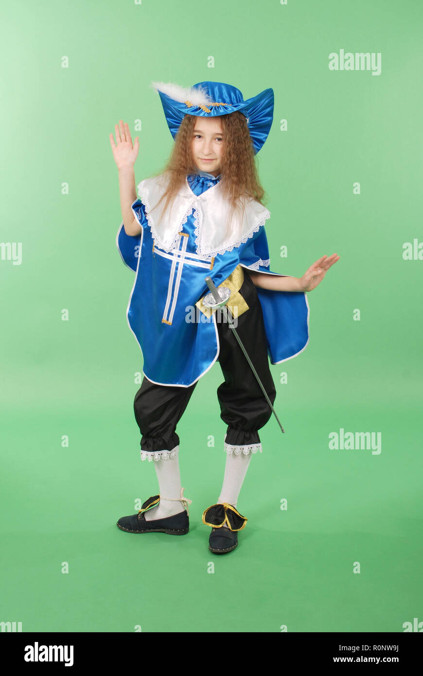 Young girl as a musketeer in blue costume with lovely blue hat with feathers on green background Stock Photo