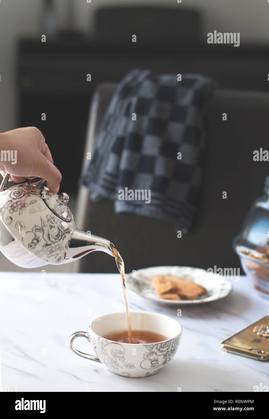 Human hand pouring a cup of tea Stock Photo