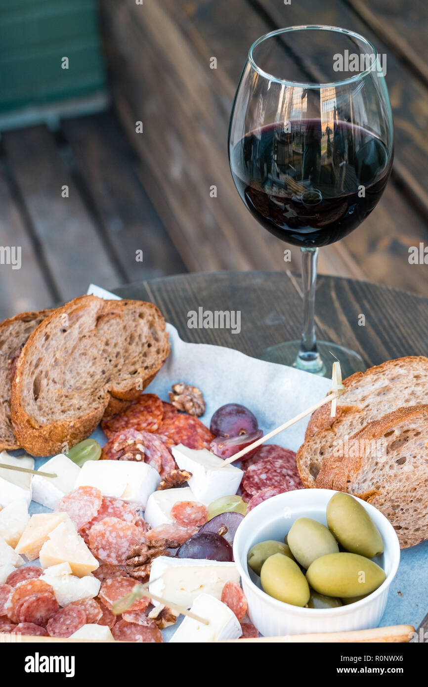 Close-up of cheese, charcuterie, olives, grapes and bread on a table with a glass of red wine Stock Photo