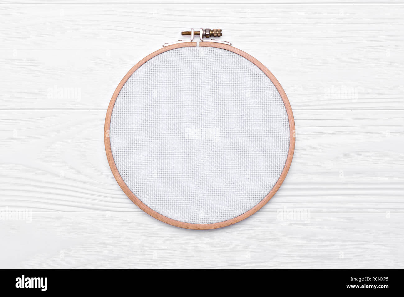 Tools for cross stitch. A hoop for embroidery and canvas on white wooden  background. Mockup for hobby Stock Photo - Alamy