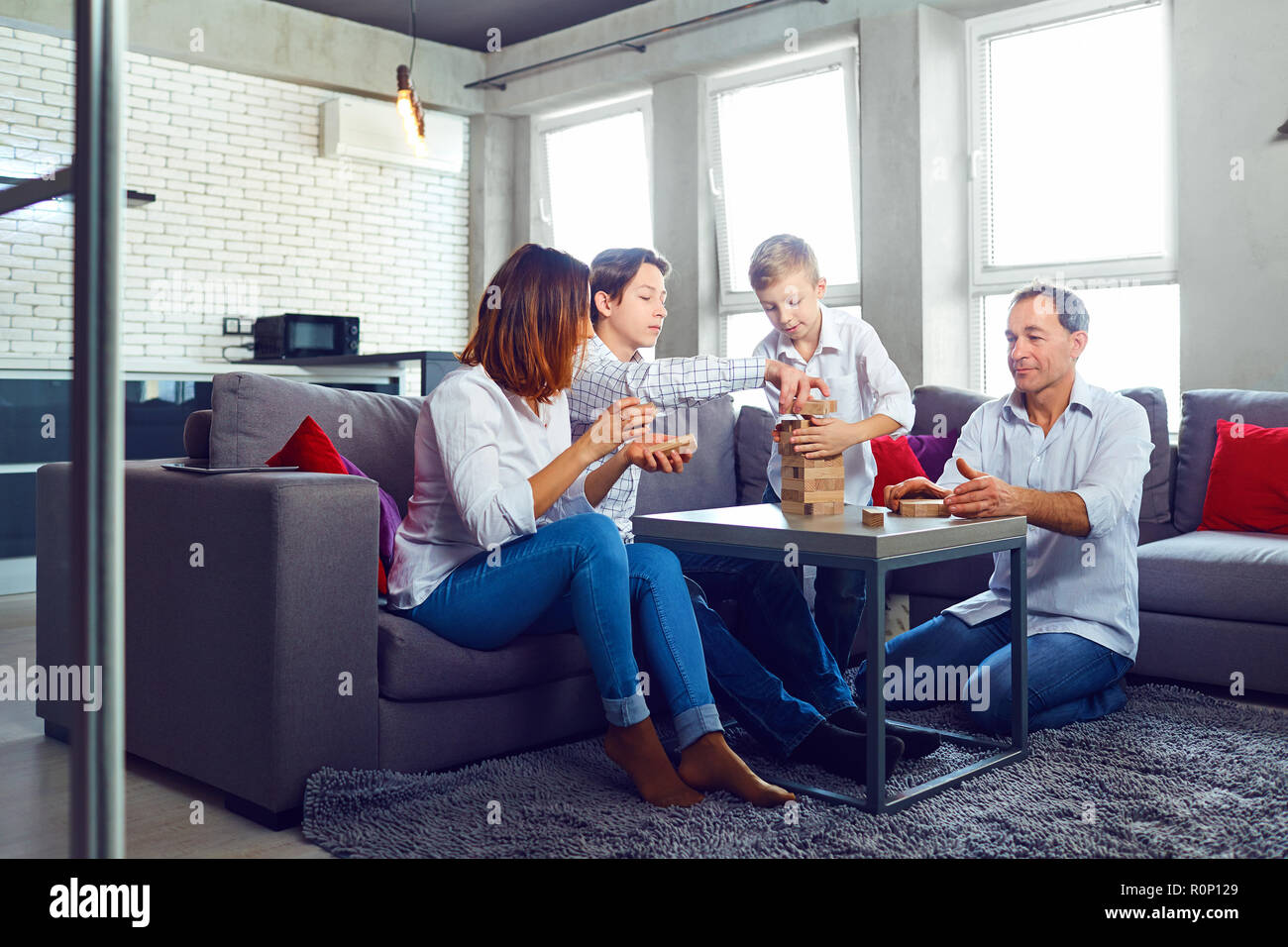 The family plays board games gaily while sitting at the table. Stock Photo
