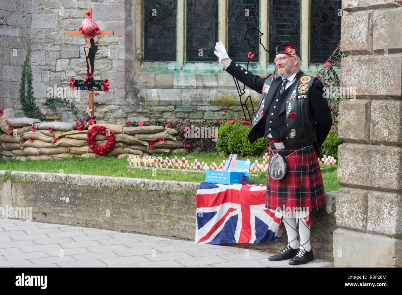 Poppy seller wearing a uniform with a kilt selling poppies for the Royal British Legion charity outside a church Stock Photo