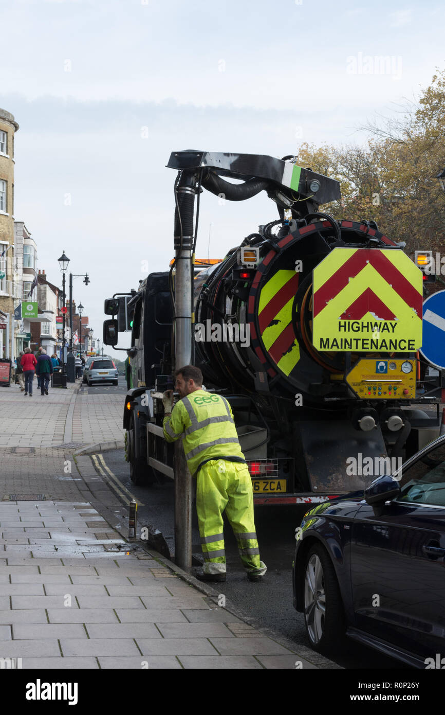 Workman using heavy machinery to clear a drain in the street Stock Photo
