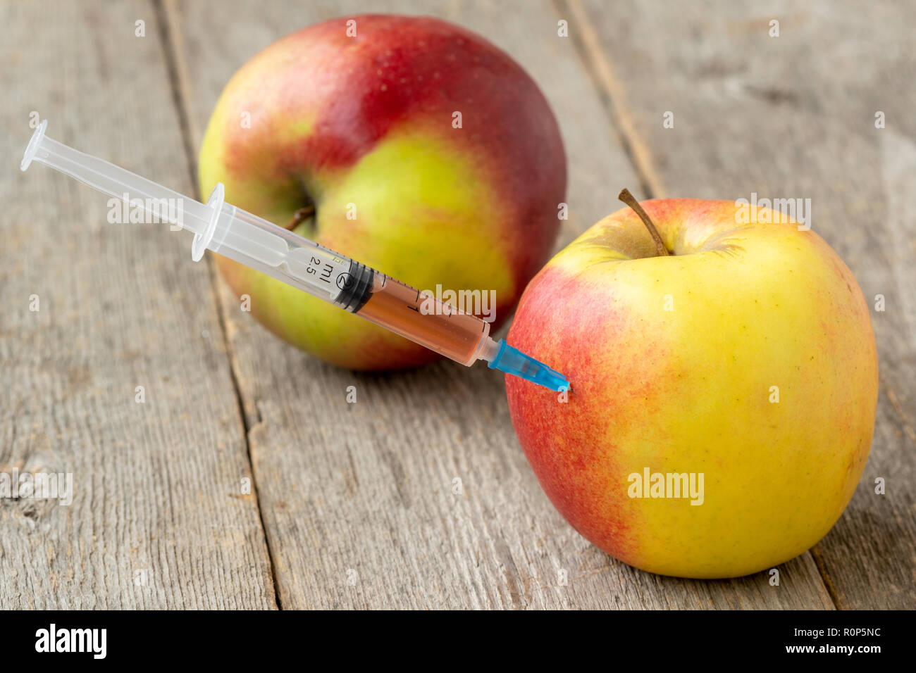 Syringe in apple. Concept for genetically modified food and cosmetic medicine Stock Photo