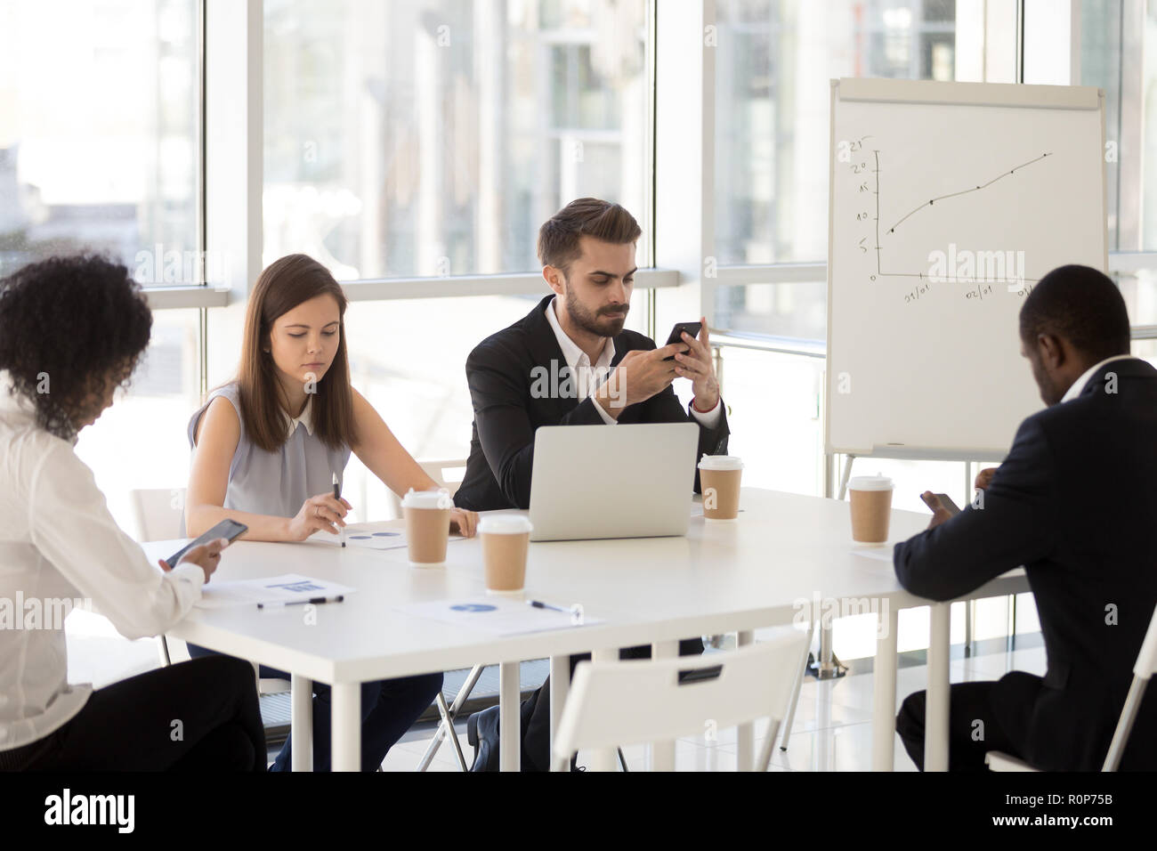 Diverse employees sitting at table using smartphones Stock Photo