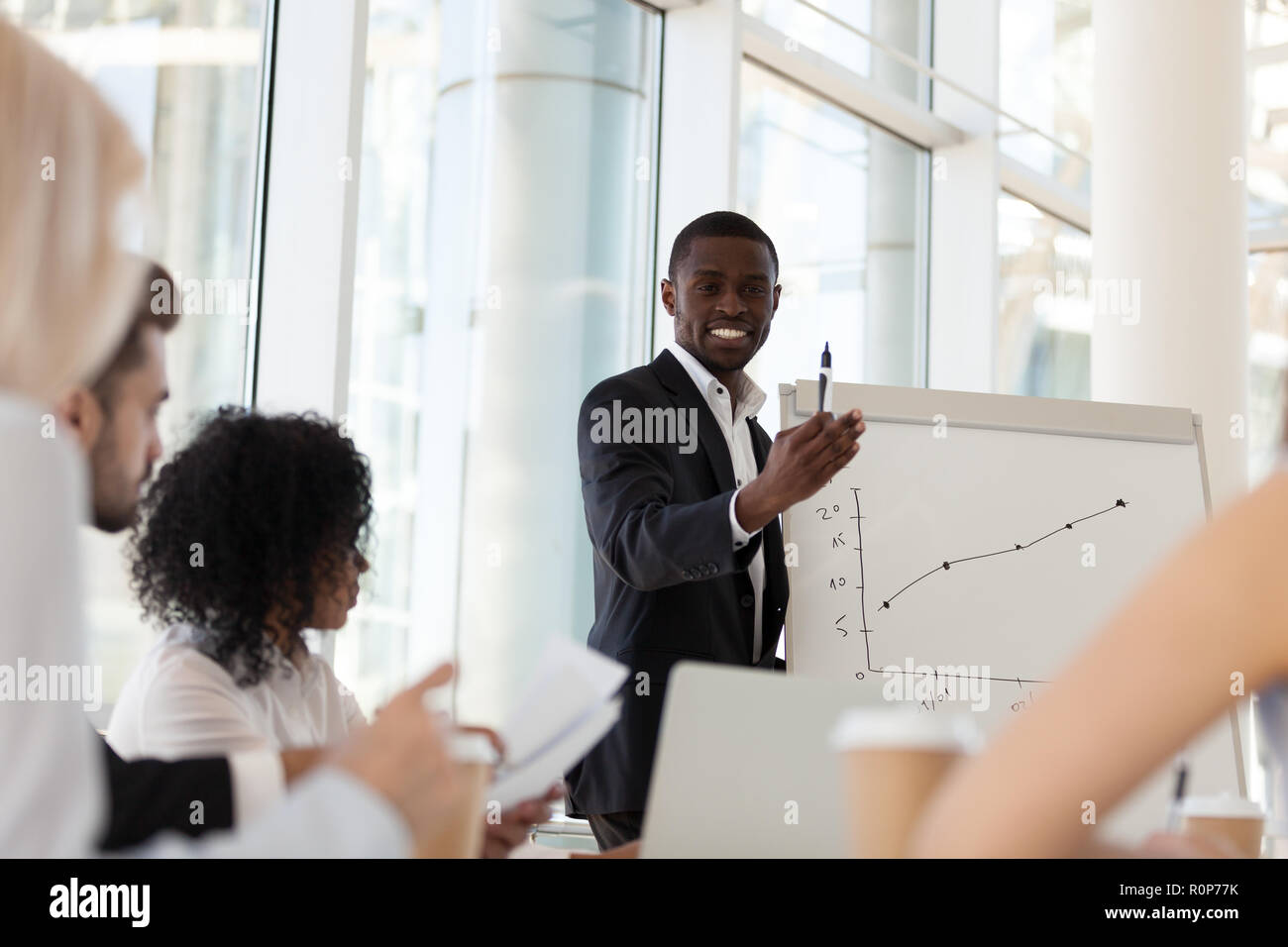 Smiling African American coach give flipchart presentation to em Stock Photo