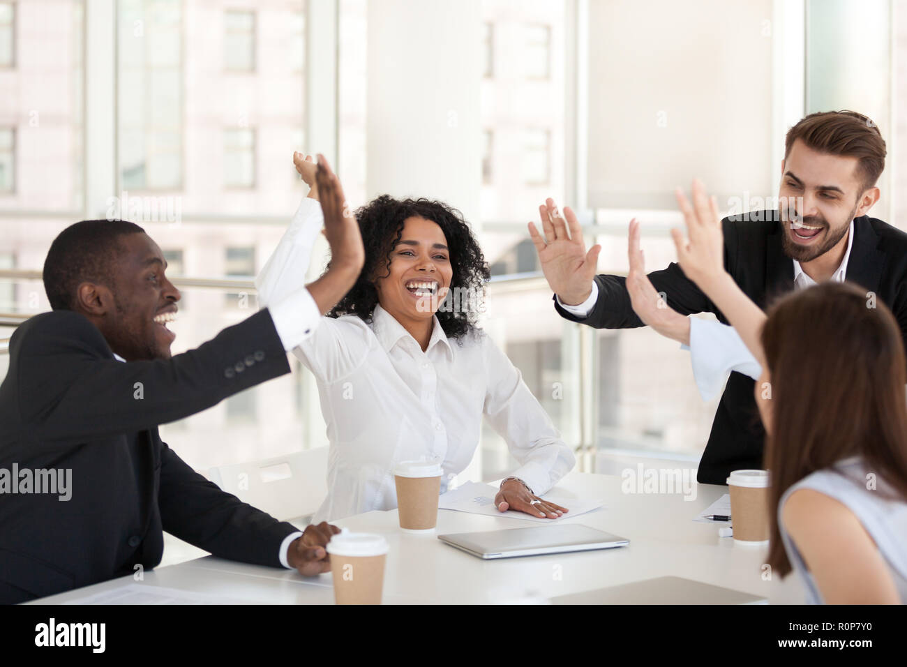 Excited diverse employees give high five at team meeting Stock Photo ...