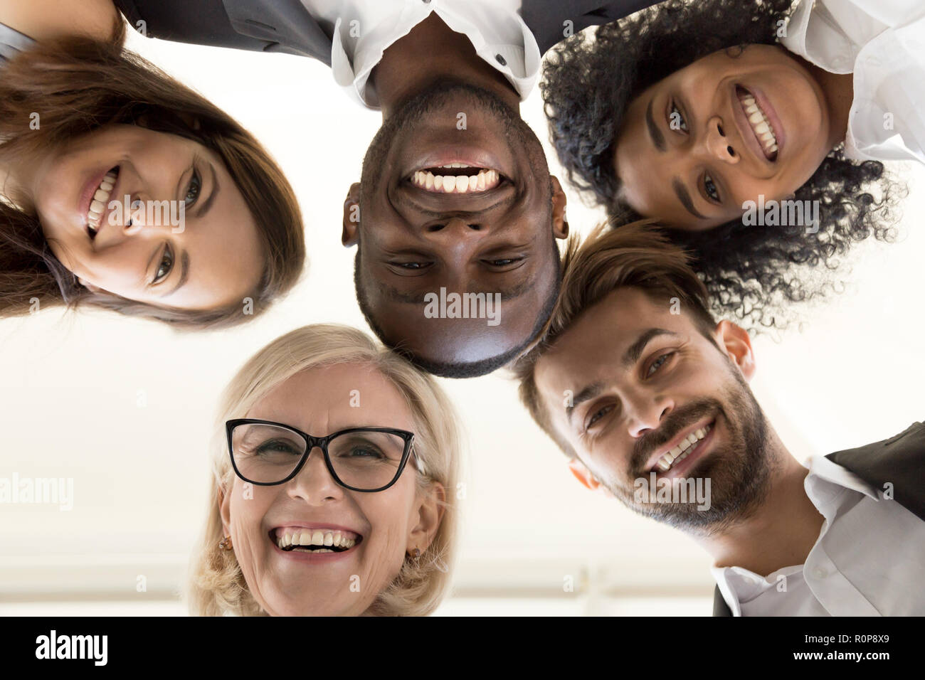 Low angle shot of excited work employees standing in circle Stock Photo