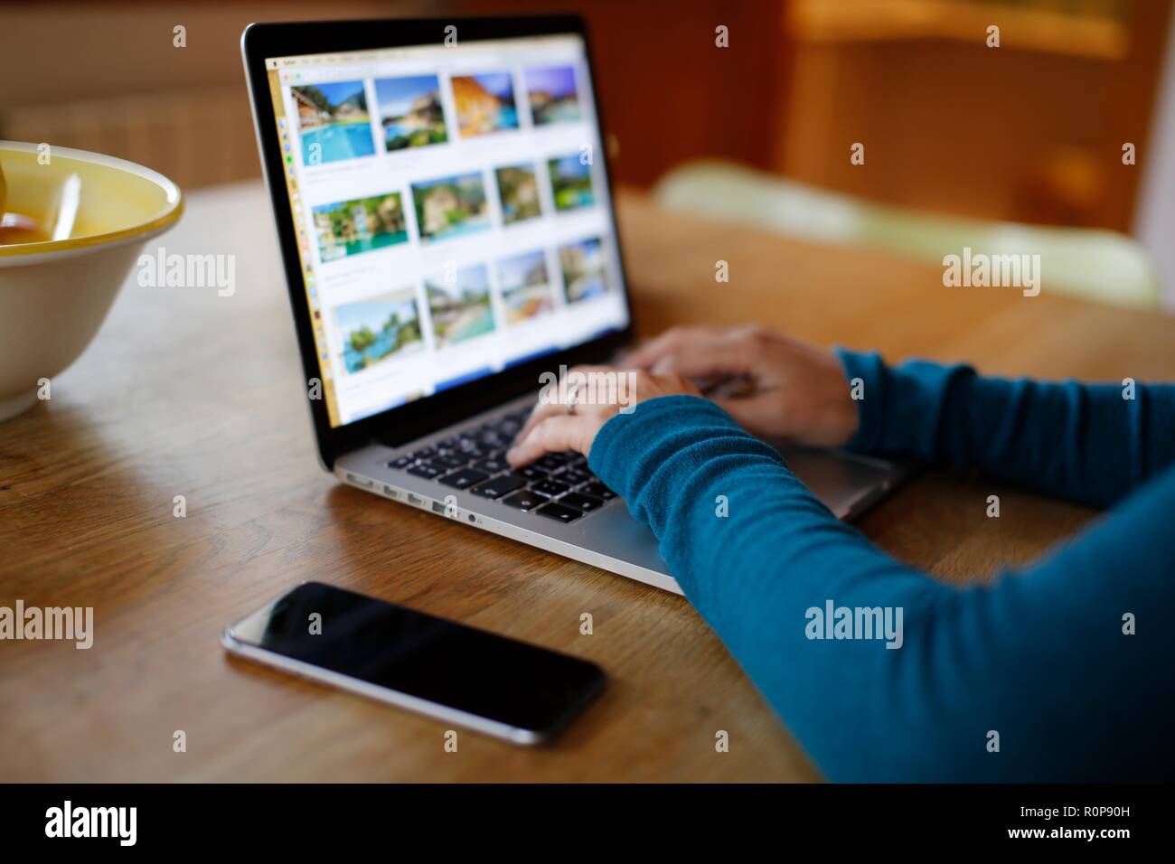 Close up of Woman's hands typing on keyboard on kitchen table Stock Photo
