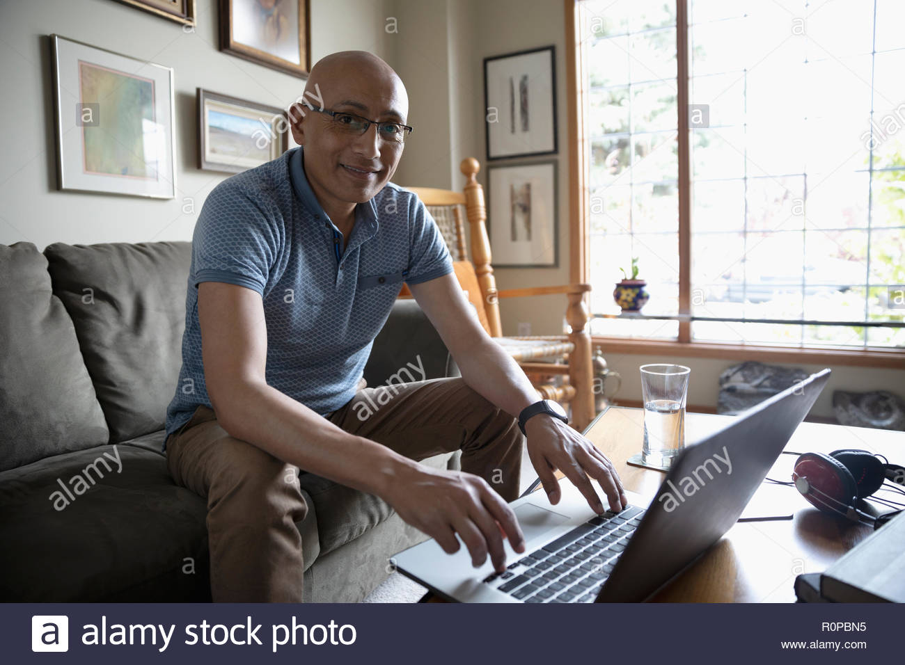 Portrait confident Latinx man using laptop in living room Stock Photo