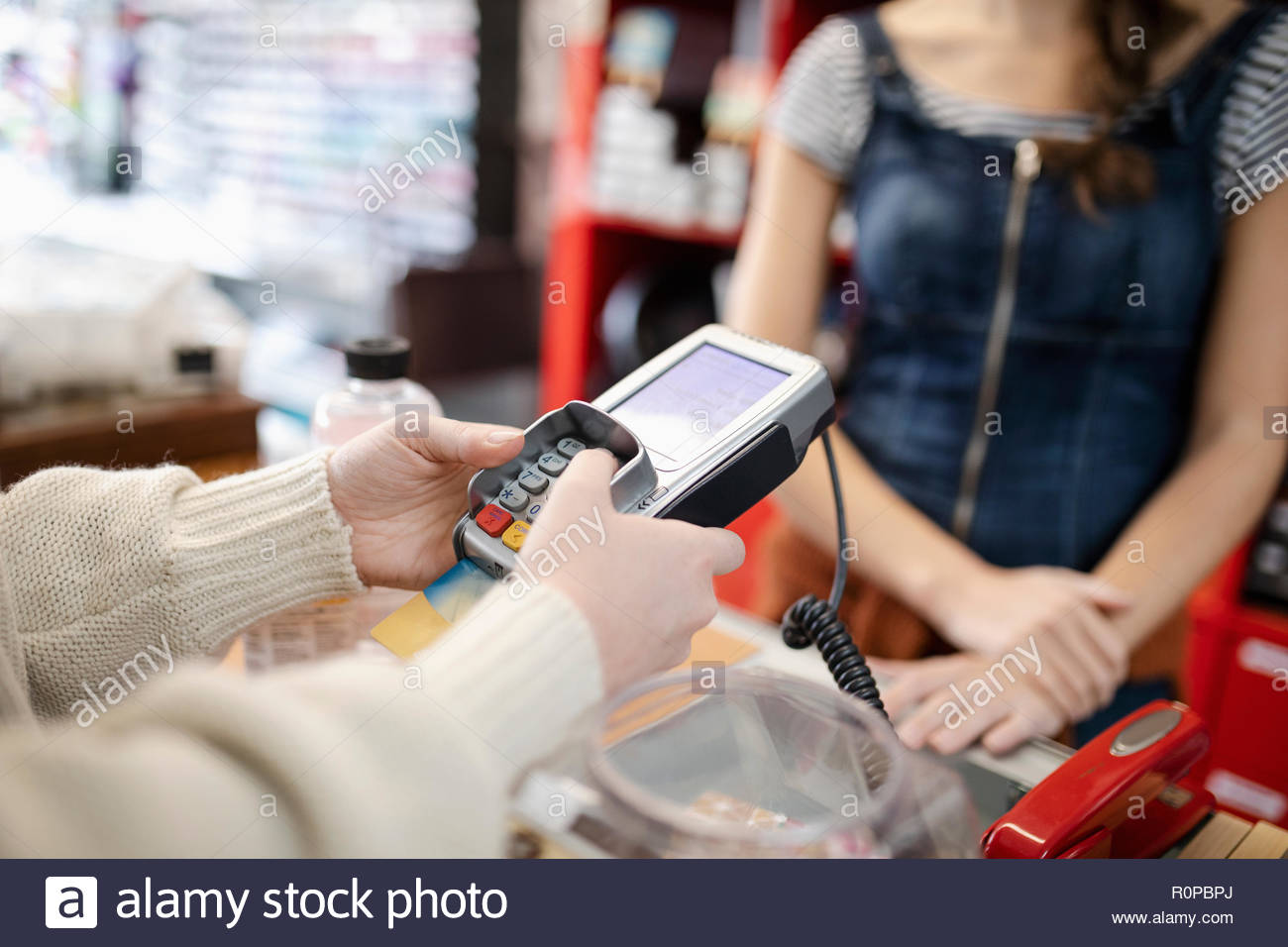 Close up female shopper paying, using credit card reader pin entry