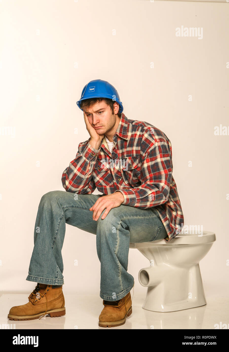 Depressed builder, sitting on an uninstalled toilet Stock Photo