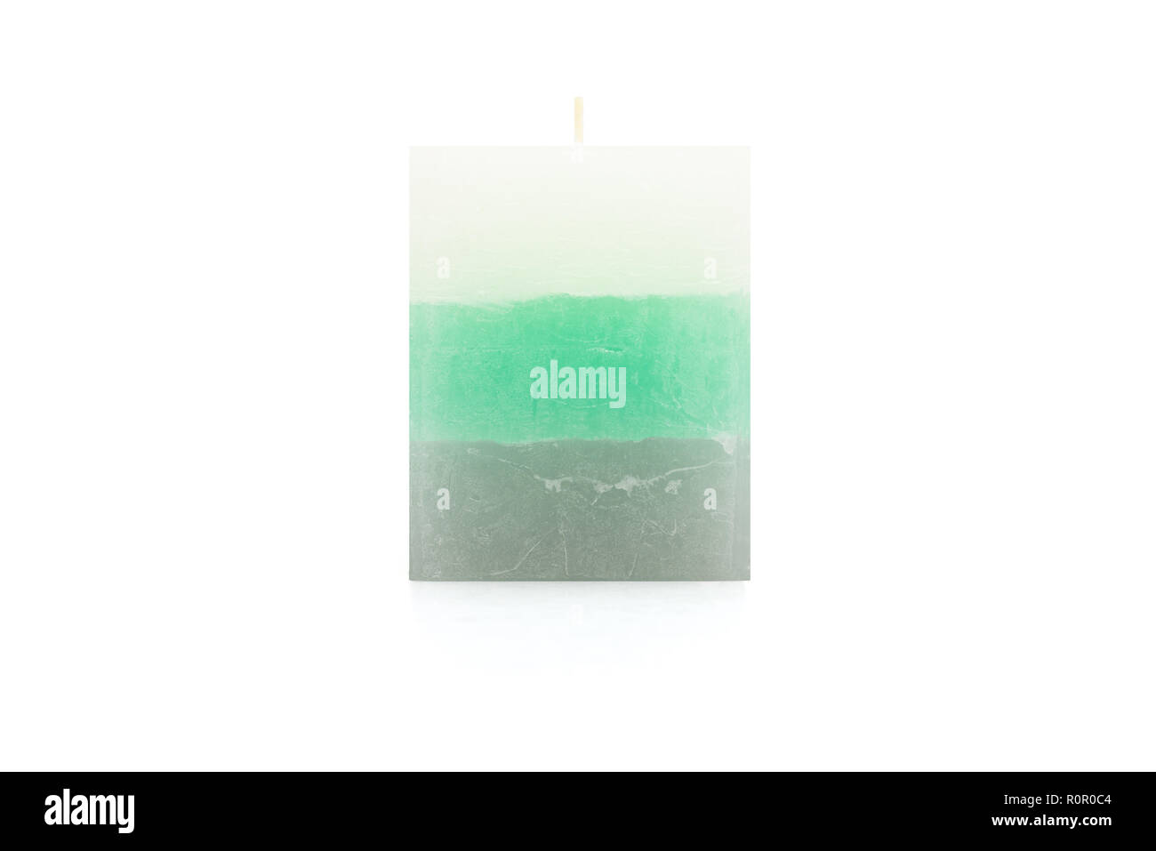 A paraffin small, square, candle in sea color lies on a white