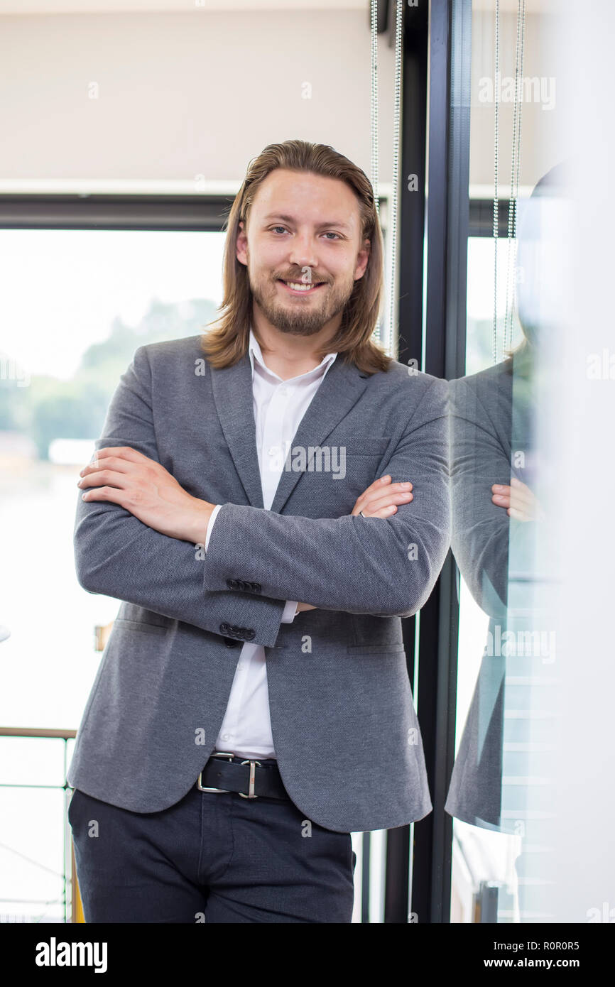 Portrait of happy businessman with arms crossed standing in office ...