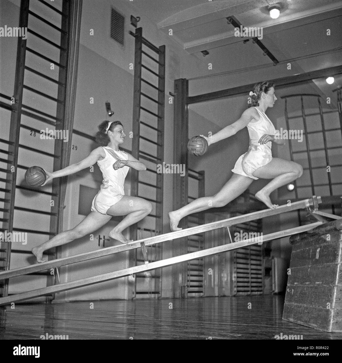Gymnastics in the 1940s. Two young women are balancing on gymnasium equipment and at the same time synchronizing their movements holding balls. 1940s Sweden Photo Kristoffersson ref AN70-4 Stock Photo
