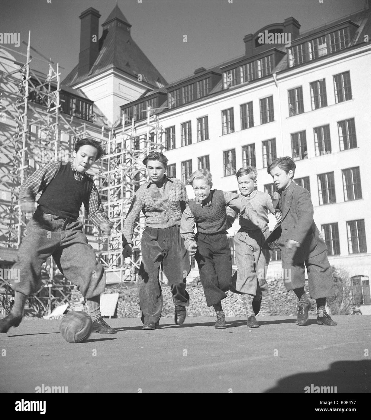 1940s boy playing soccer. A group of boys dressed in typical 1940s trousers are playing football on the school yard. Sweden 1940s Photo Kristoffersson ref AE25-4 Stock Photo