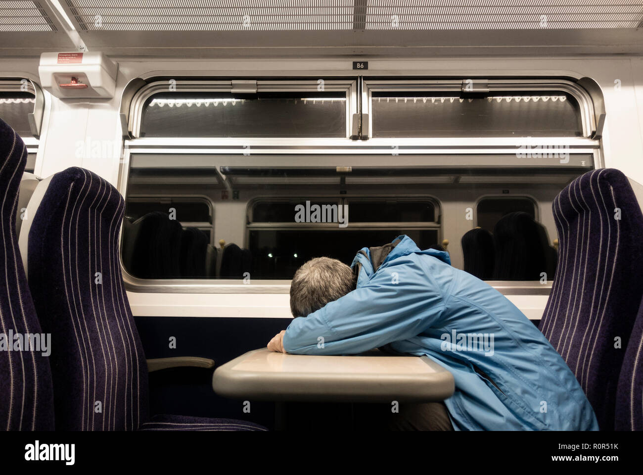 Man sleeping on train at night. UK Stock Photo