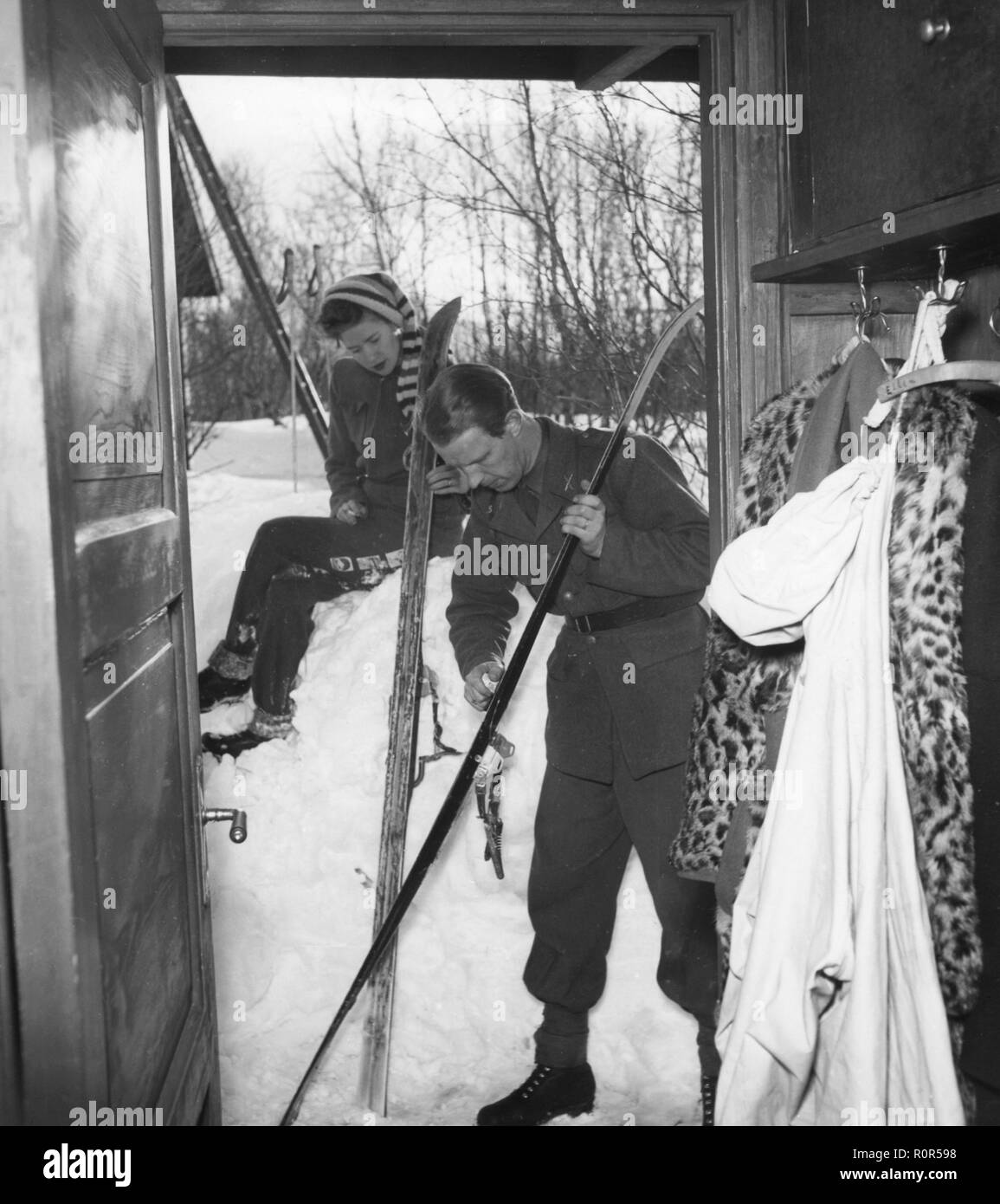 Winter in the 1940s. A young couple are going skiing and prepares the skis with ski wax to get better traction on the snow.   Sweden 1943. Photo Kristoffersson ref D115-4 Stock Photo