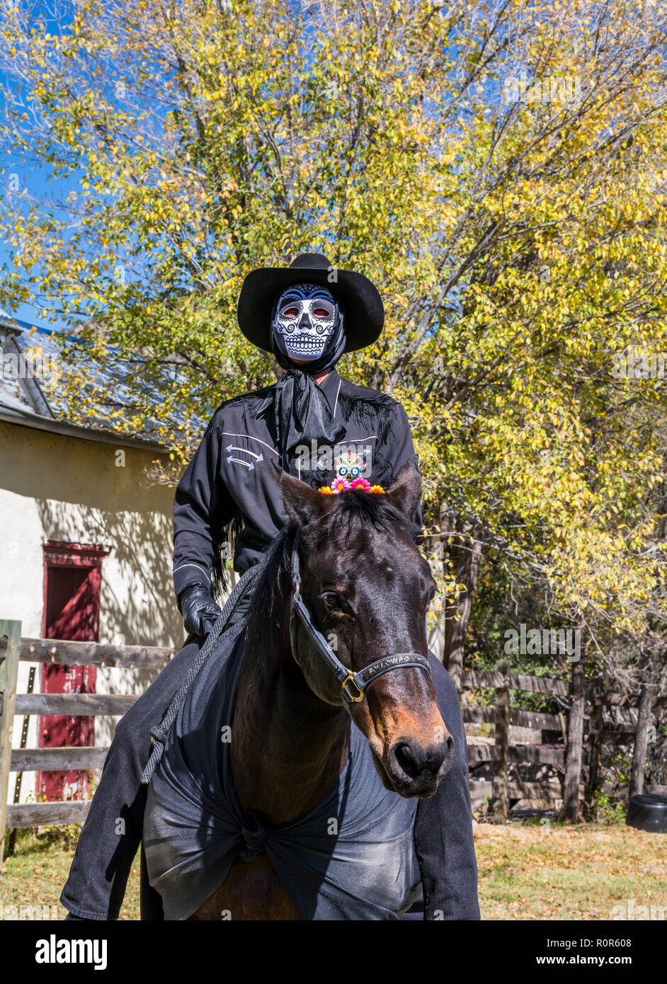 Day of the Dead, Dia de los Muertos, ghost rider, man wearing a mask and a cowboy hat riding a dark horse, Lincoln New Mexico, USA. Stock Photo