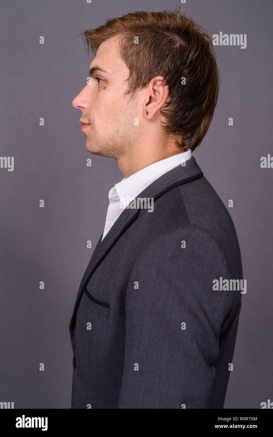 Portait of young handsome businessman against gray background Stock Photo