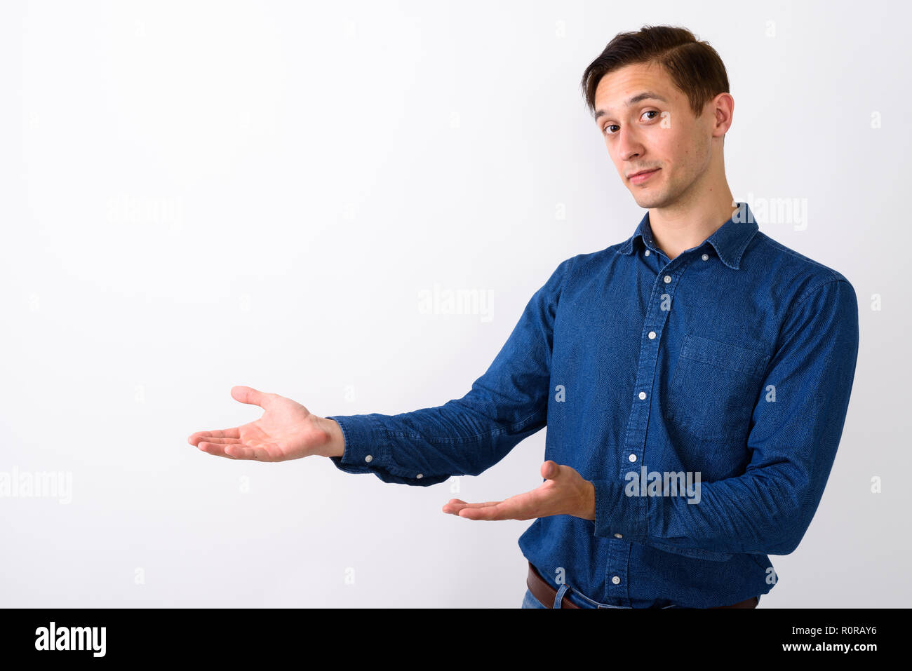 Studio shot of young handsome man against showing something whit Stock Photo