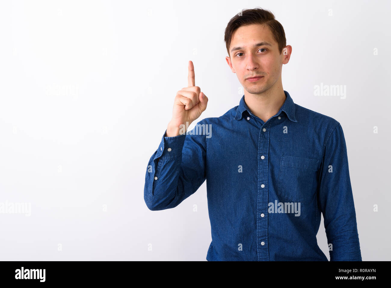 Studio shot of young handsome man pointing finger up against whi Stock Photo
