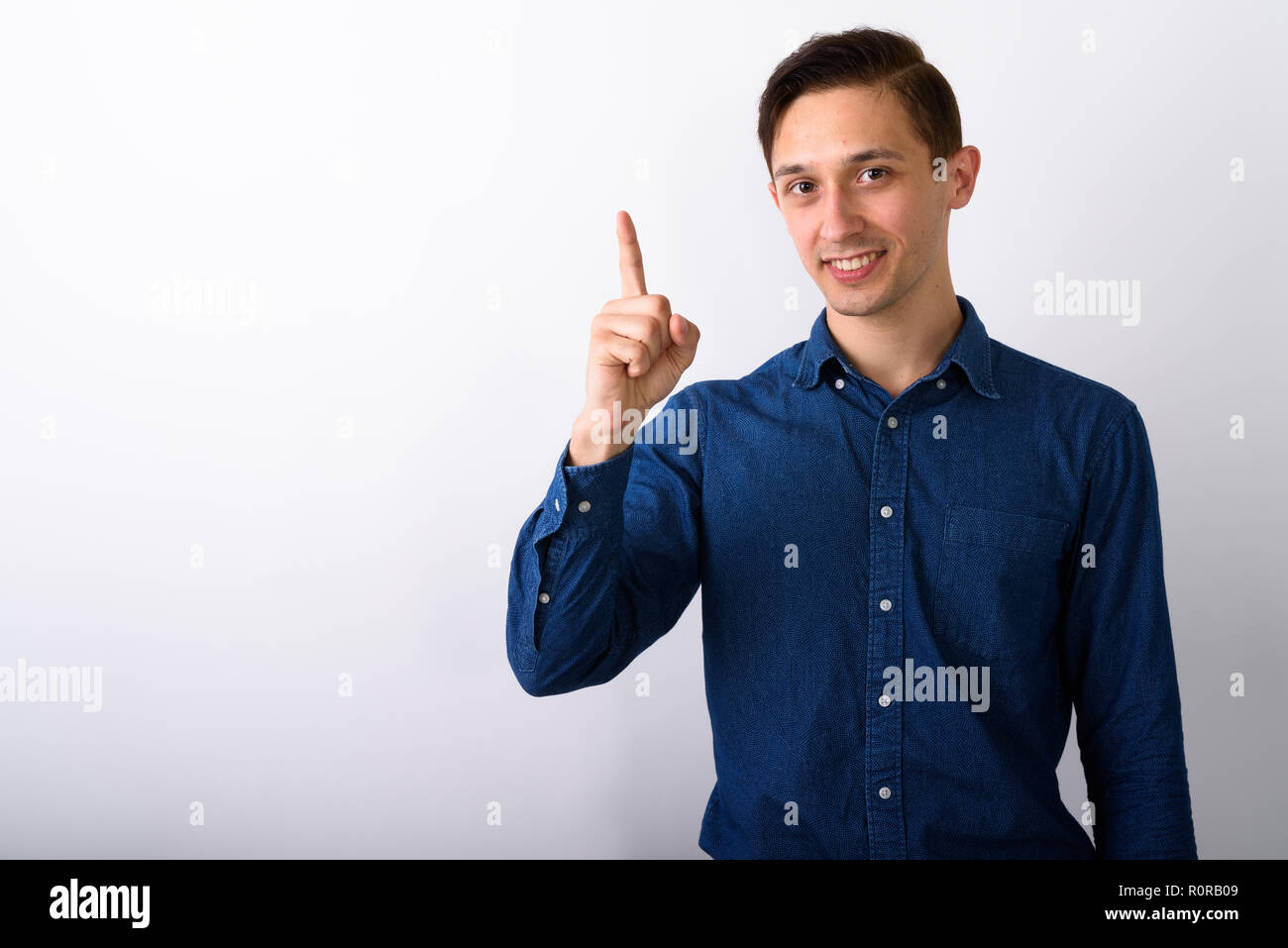 Studio shot of happy young handsome man smiling while pointing f Stock Photo