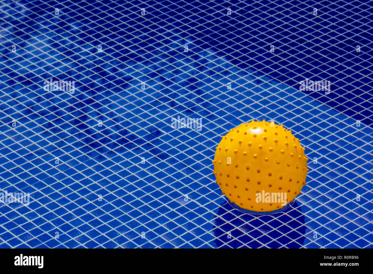 Yellow ball in the middle of a big textured pool, representing a unique value, a total individual being Stock Photo