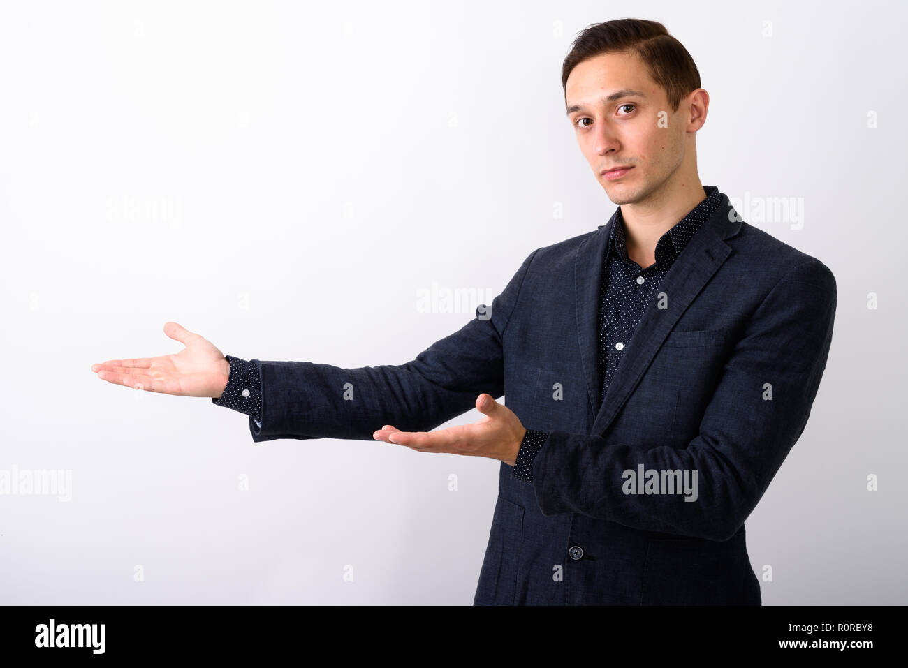 Studio shot of young handsome businessman showing something agai Stock Photo