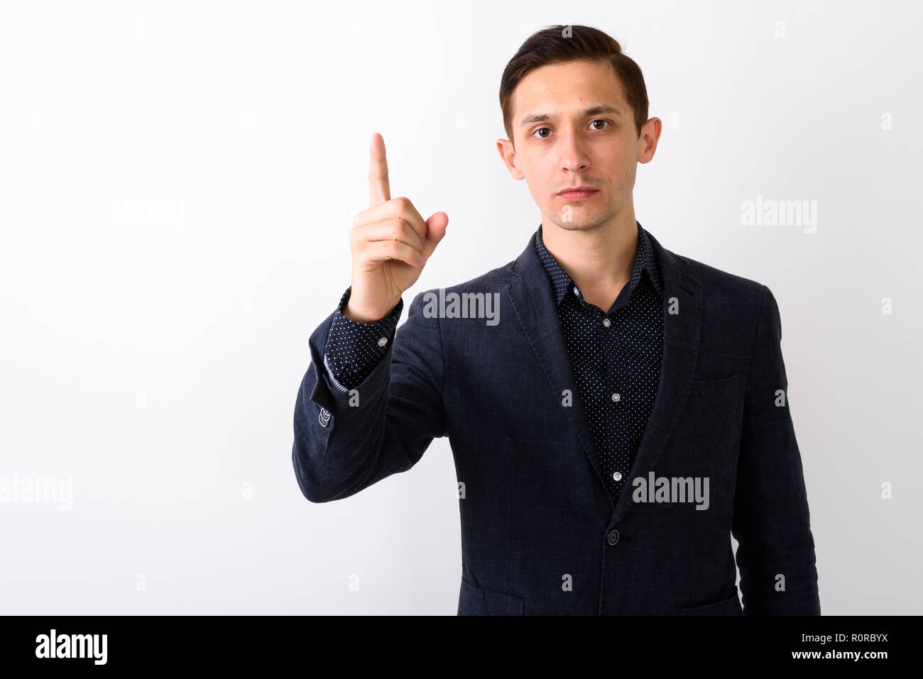 Studio shot of young handsome businessman pointing finger up aga Stock Photo