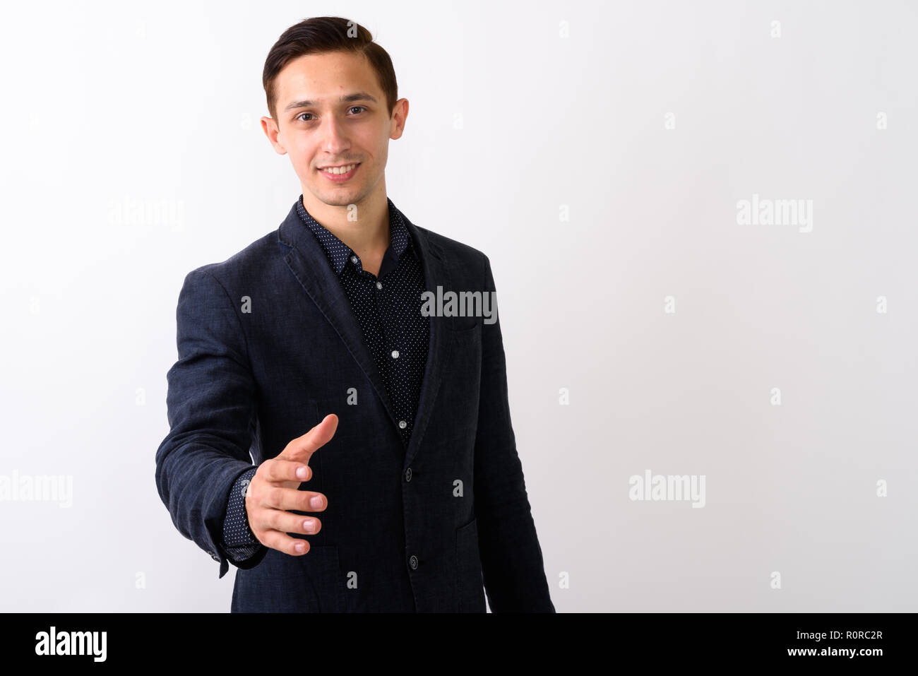 Studio shot of young happy businessman smiling while giving hand Stock Photo