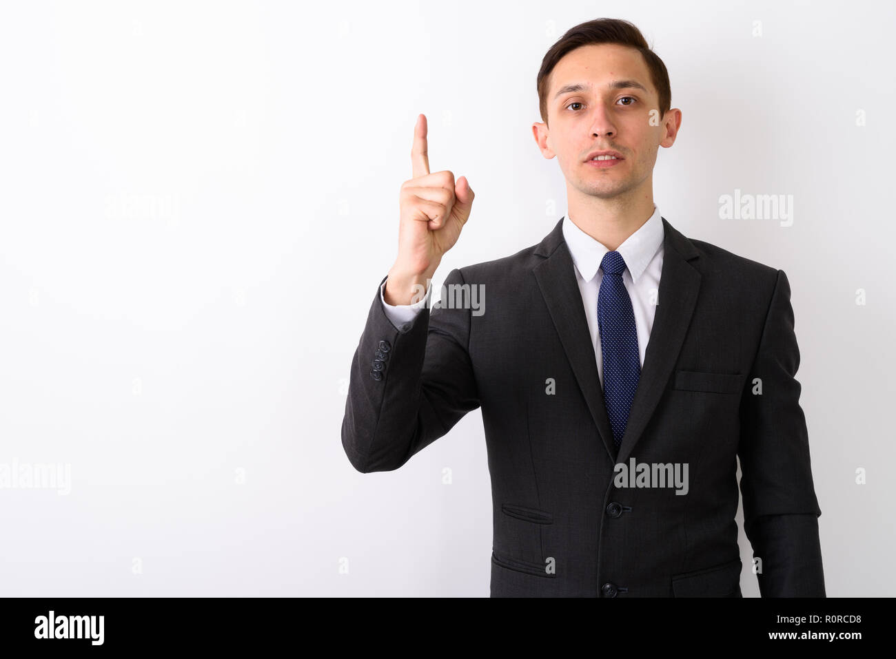 Studio shot of young handsome businessman pointing finger up aga Stock Photo