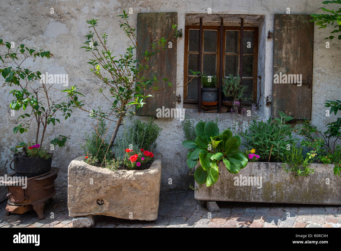 Front of a house decorated with stone planters and hanging cast iron buckets making a very beautiful street front in Annecy, France Stock Photo