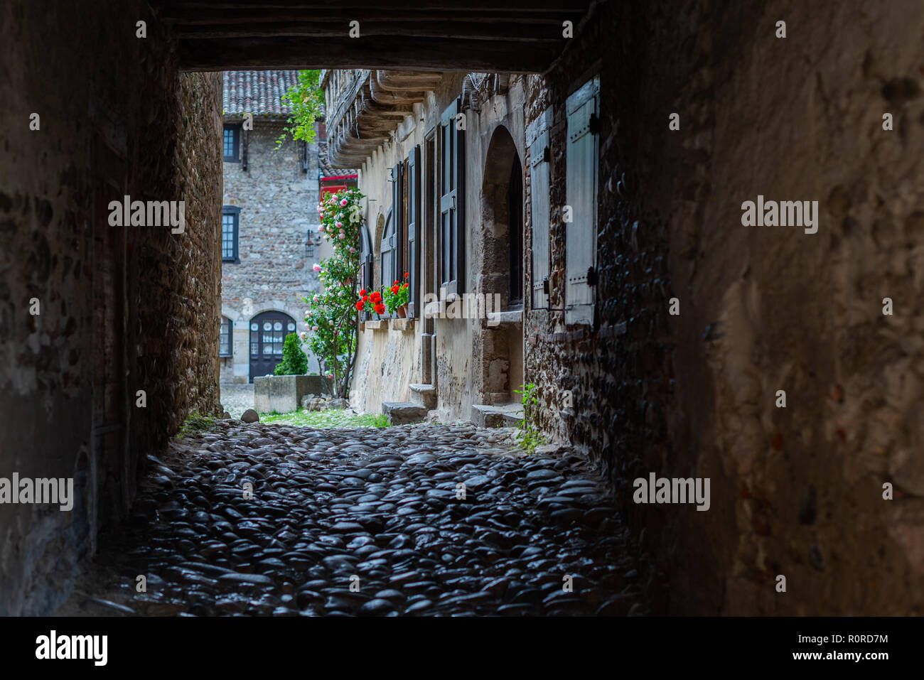 View of a cobbled courtyard framed by a square arch in the French monastery of Sainte-Croix-en-Jarez. Stock Photo