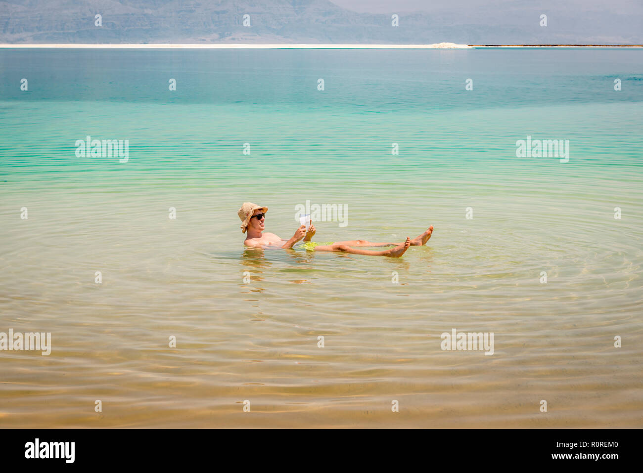 Man bathing in Dead Sea and reading, Ein Bokek Beach, Dead Sea, Kalia Beach, Israel Stock Photo