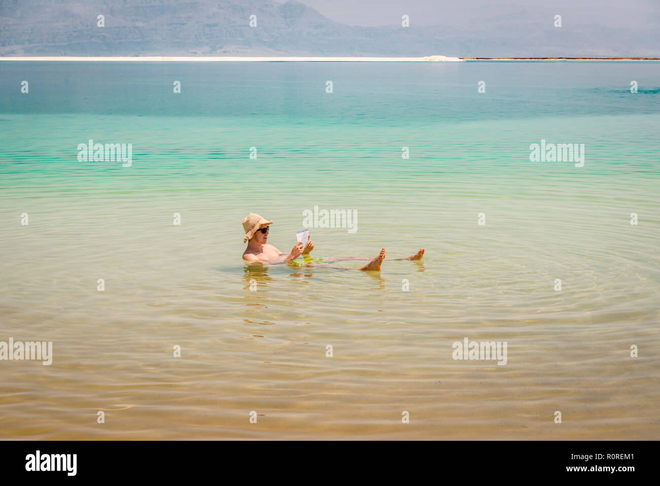 Man bathing in Dead Sea and reading, Ein Bokek Beach, Dead Sea, Kalia Beach, Israel Stock Photo