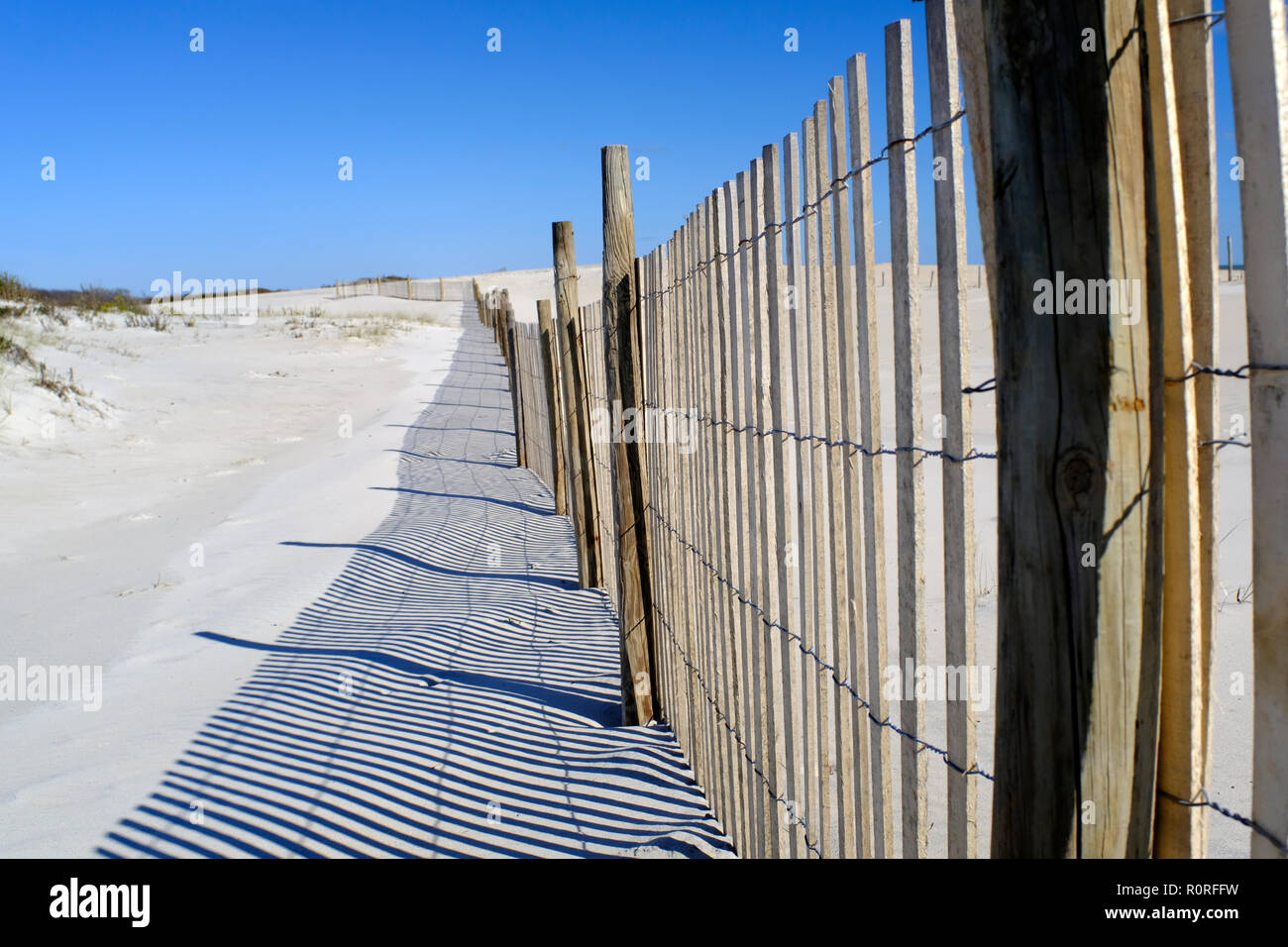 Storm fence and shadows on dunes on Assateague National Seashore Park in Maryland Stock Photo