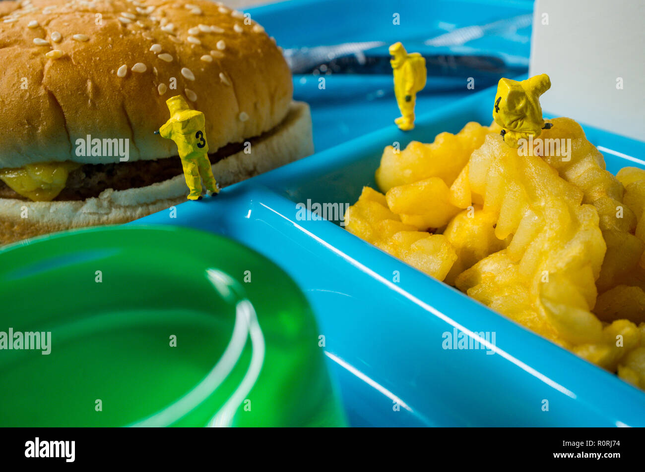 Miniature hazmat team inspecting the nutritional value of unhealthy fast food school lunch Stock Photo