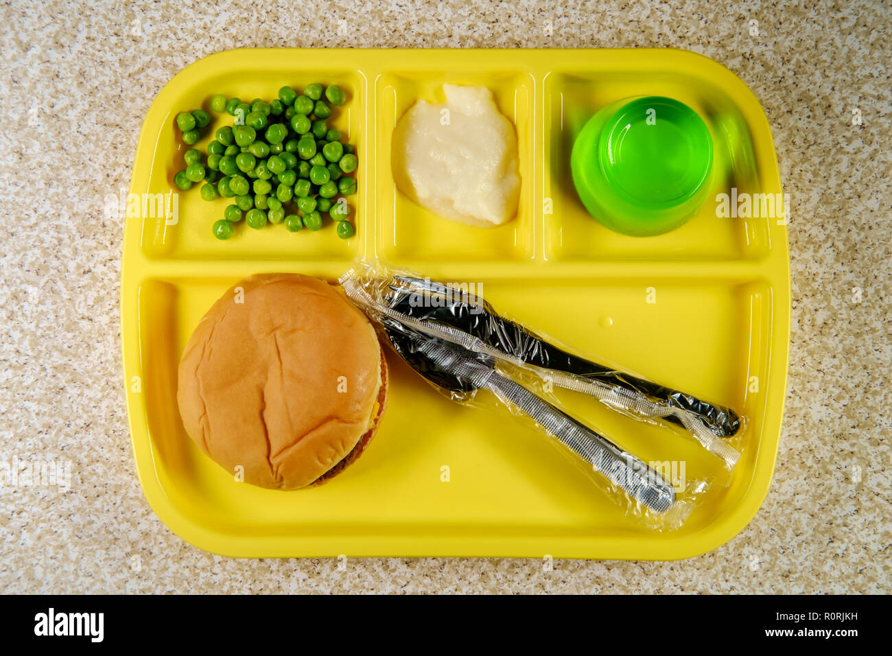 Elementary school lunch cheeseburger with mashed potatoes gelatin and green peas on portion tray Stock Photo