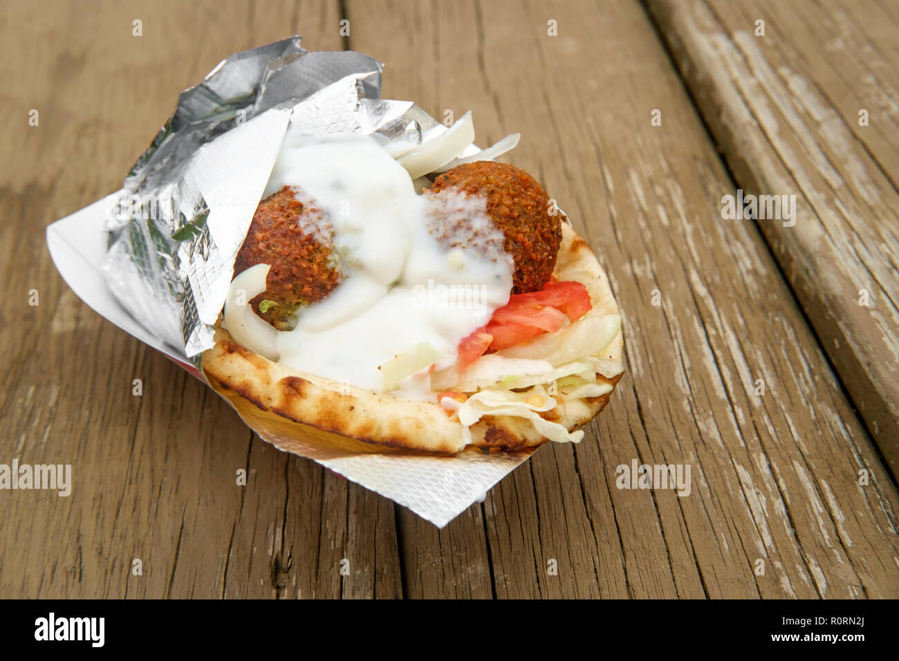 Fresh and healthy falafel with tzatziki tomato red onion and iceberg lettuce in pita bread Stock Photo