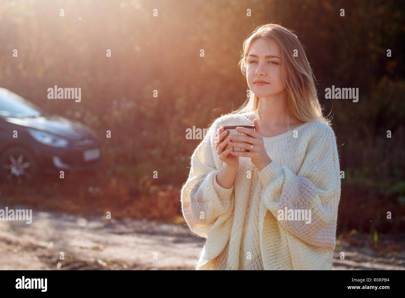 Beautiful admiring woman drinking hot tea from thermos cup Stock Photo