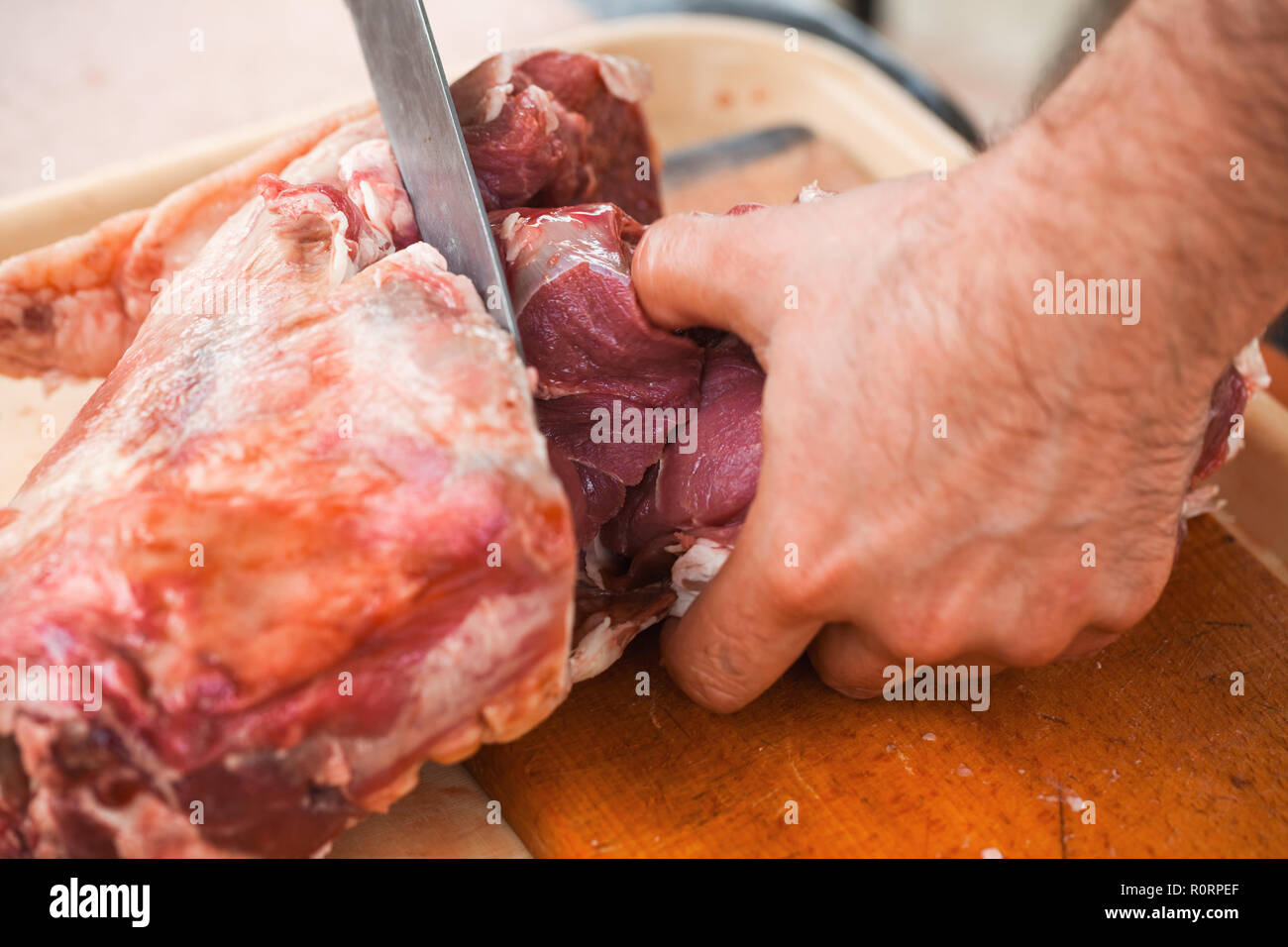Lamb cutting, cook hands with knife, close-up photo, selective focus Stock Photo