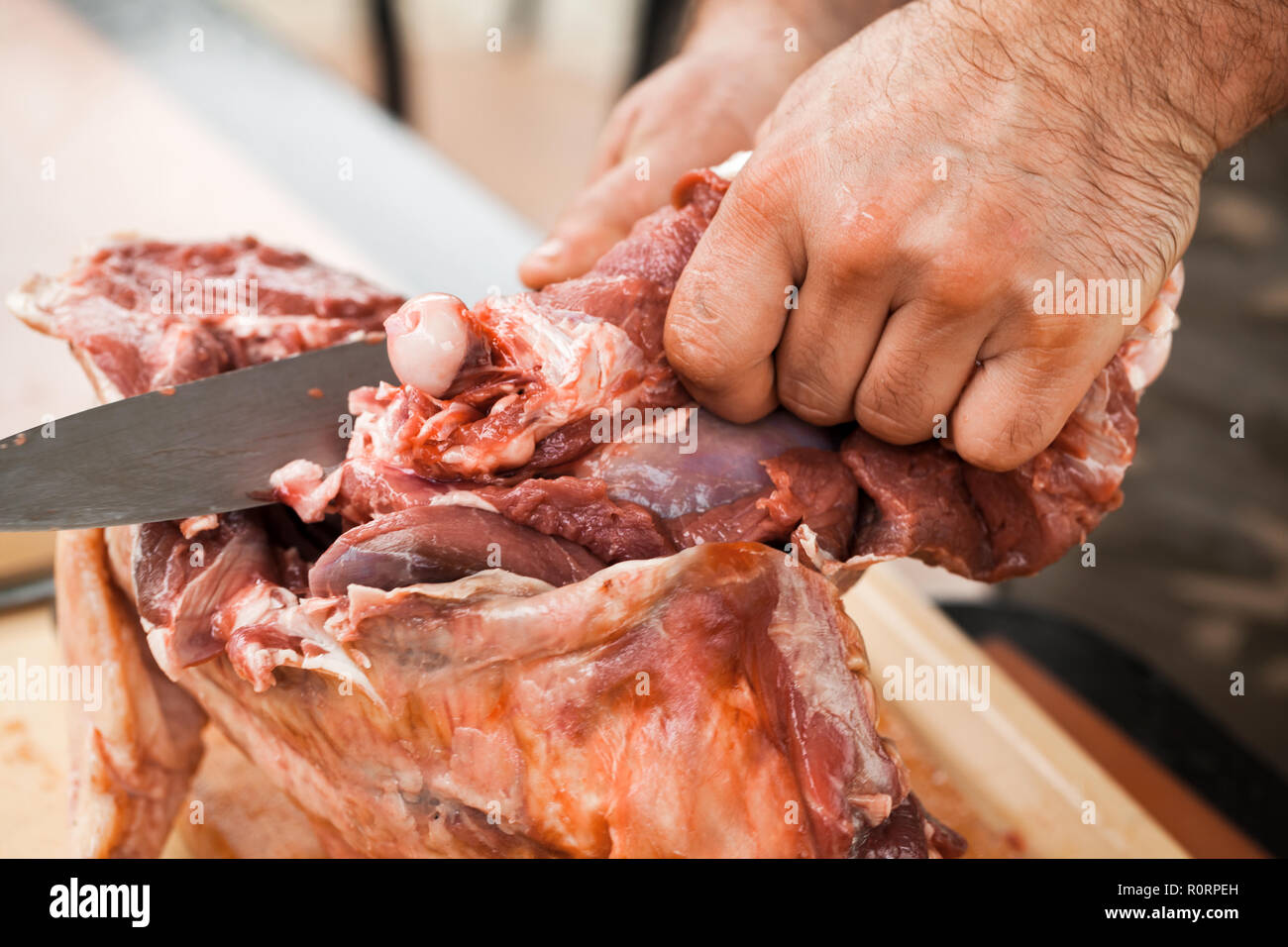 Raw lamb cutting, cook hands with knife, close-up photo, selective focus Stock Photo