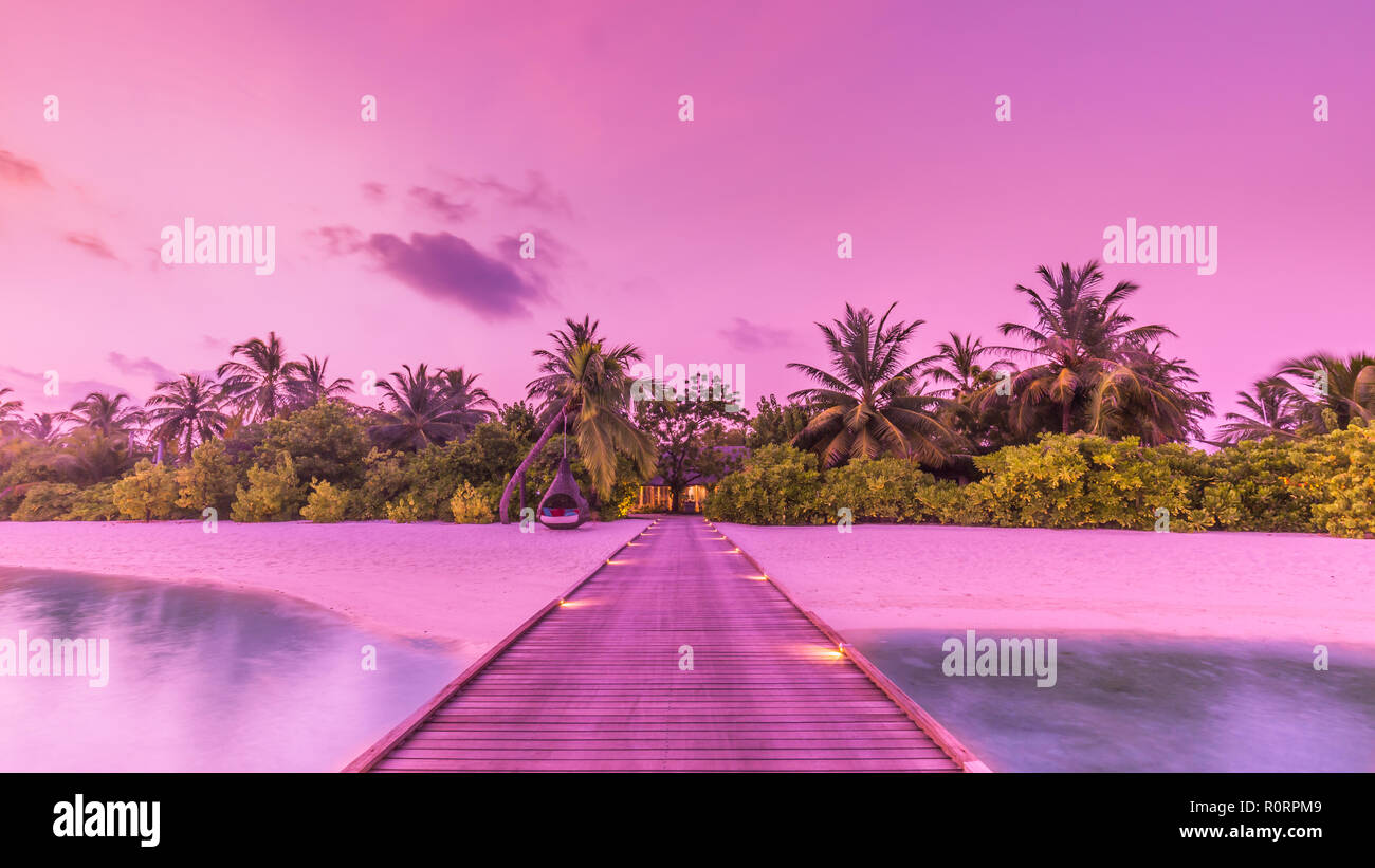 Amazing sunset sky and reflection on calm sea, Maldives beach landscape of luxury over water pier. Exotic scenery of summer vacation and holiday Stock Photo