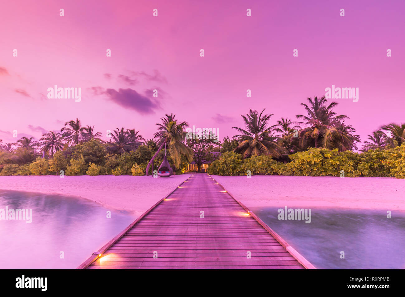 Amazing sunset sky and reflection on calm sea, Maldives beach landscape of luxury over water pier. Exotic scenery of summer vacation and holiday Stock Photo