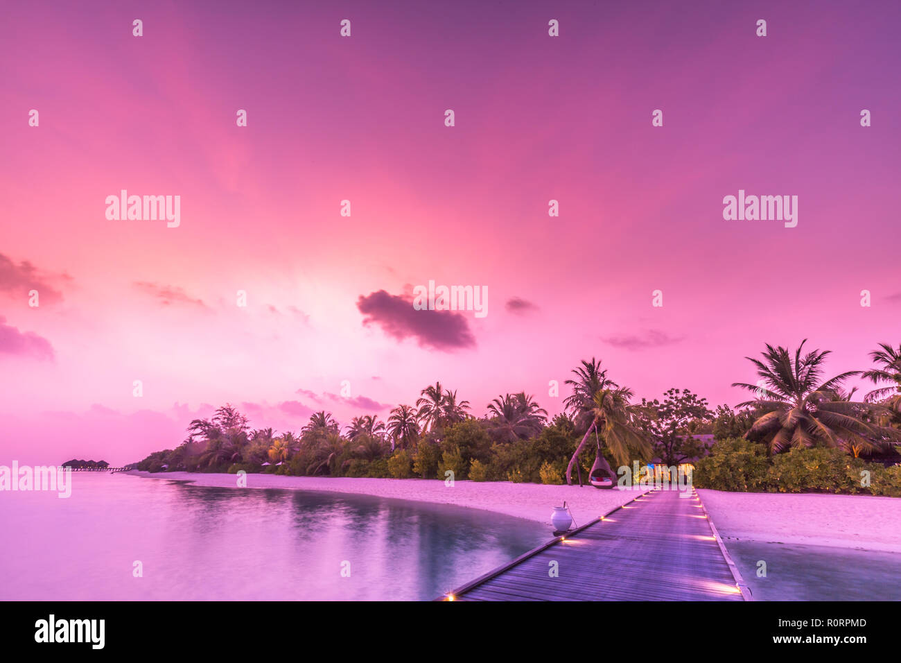 Amazing sunset sky and reflection on calm sea, Maldives beach landscape of luxury over water pier. Exotic scenery of summer vacation and holiday Stock Photo