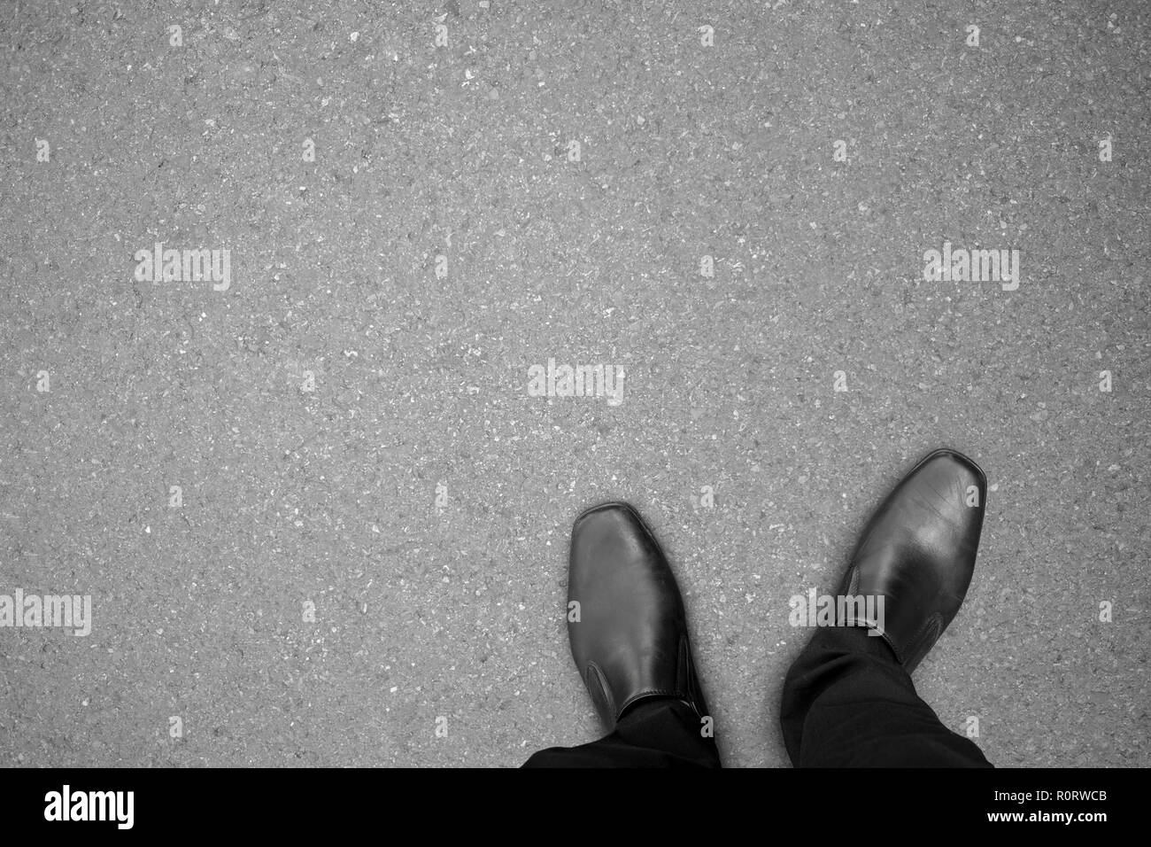 Businessman in black shoes standing on concrete road in relax action and making decision what to do next. Stock Photo