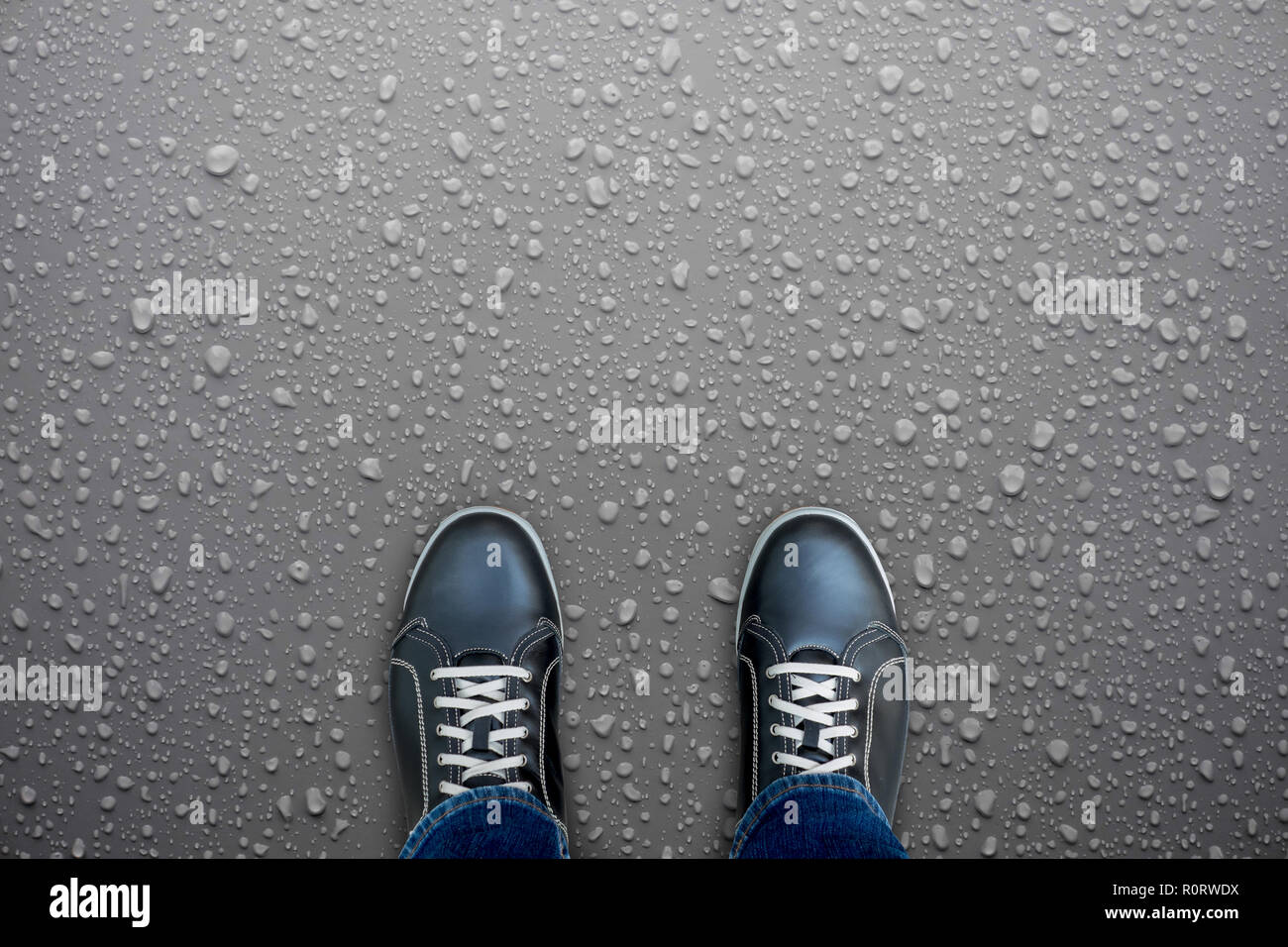 Caution, wet floor. Black shoes standing on wet floor. Slippery and