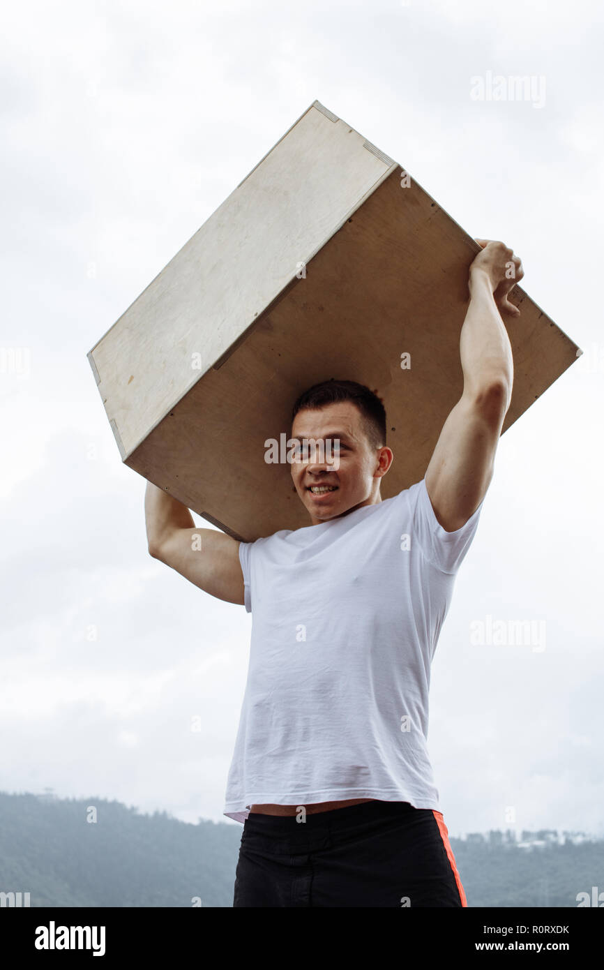 Cross Fit Weight Lifting exercise man workout outdoor, lifting heavy jump box. Stock Photo